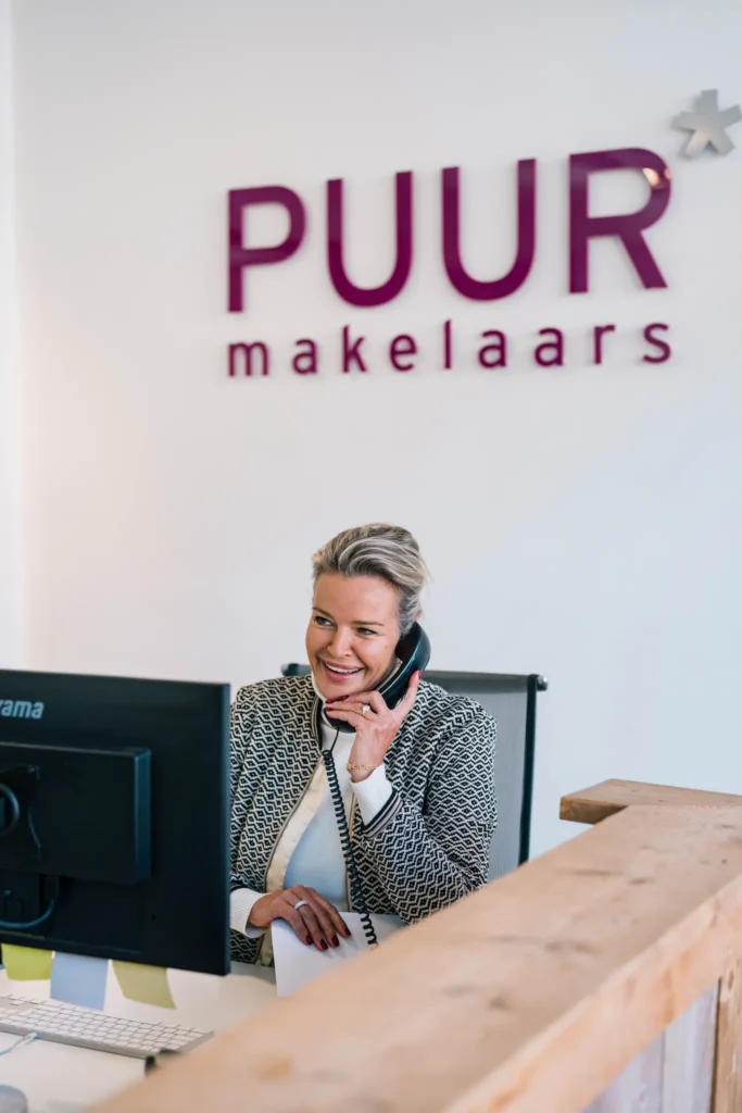 Een vrouw die aan de telefoon praat in een makelaarskantoor.